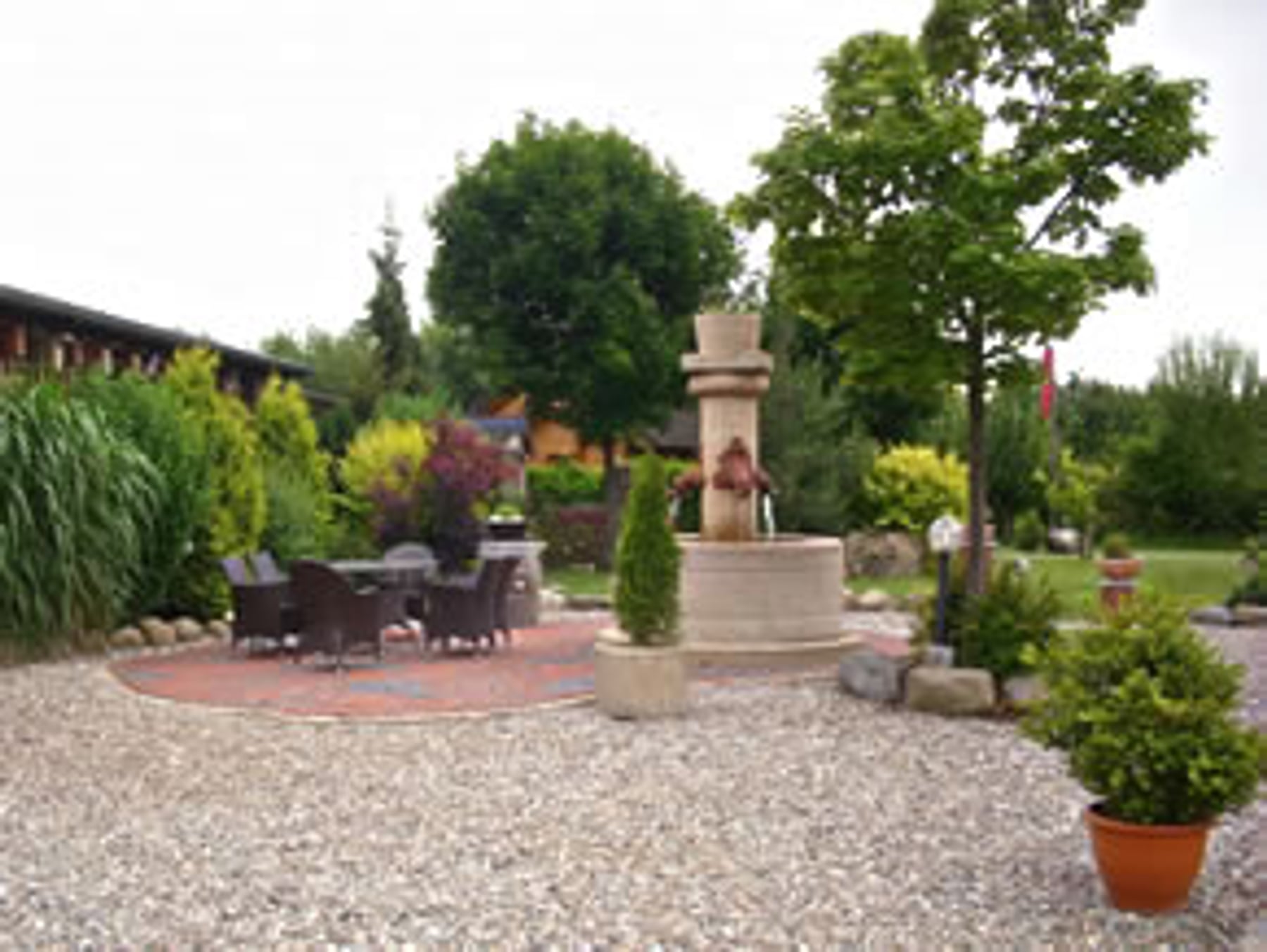 Gartenanlage mit Brunnen, Terrasse und Bäumen von Gartenbau Kern